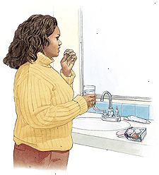 Kvinna som står vid badrum sink tar p-piller.