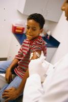 Foto av en ung pojke som förbereder sig för att få en vaccination skott från sin läkare