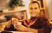 Bild på en ung man ler, med en kopp kaffe