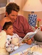 Bild på pappa lyssna på sin son läsa en bok vid sänggåendet