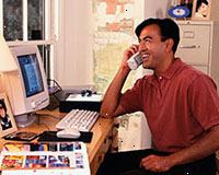 Bild på en man som arbetar på datorn, prata i telefon